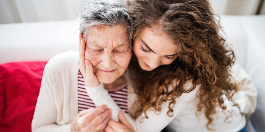 Ein junges Mädchen mit Großmutter zu Hause umarmt